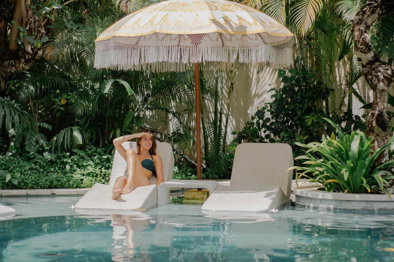 a woman sitting in a chair next to a swimming pool at Amnaya Resort Nusa Dua in Nusa Dua