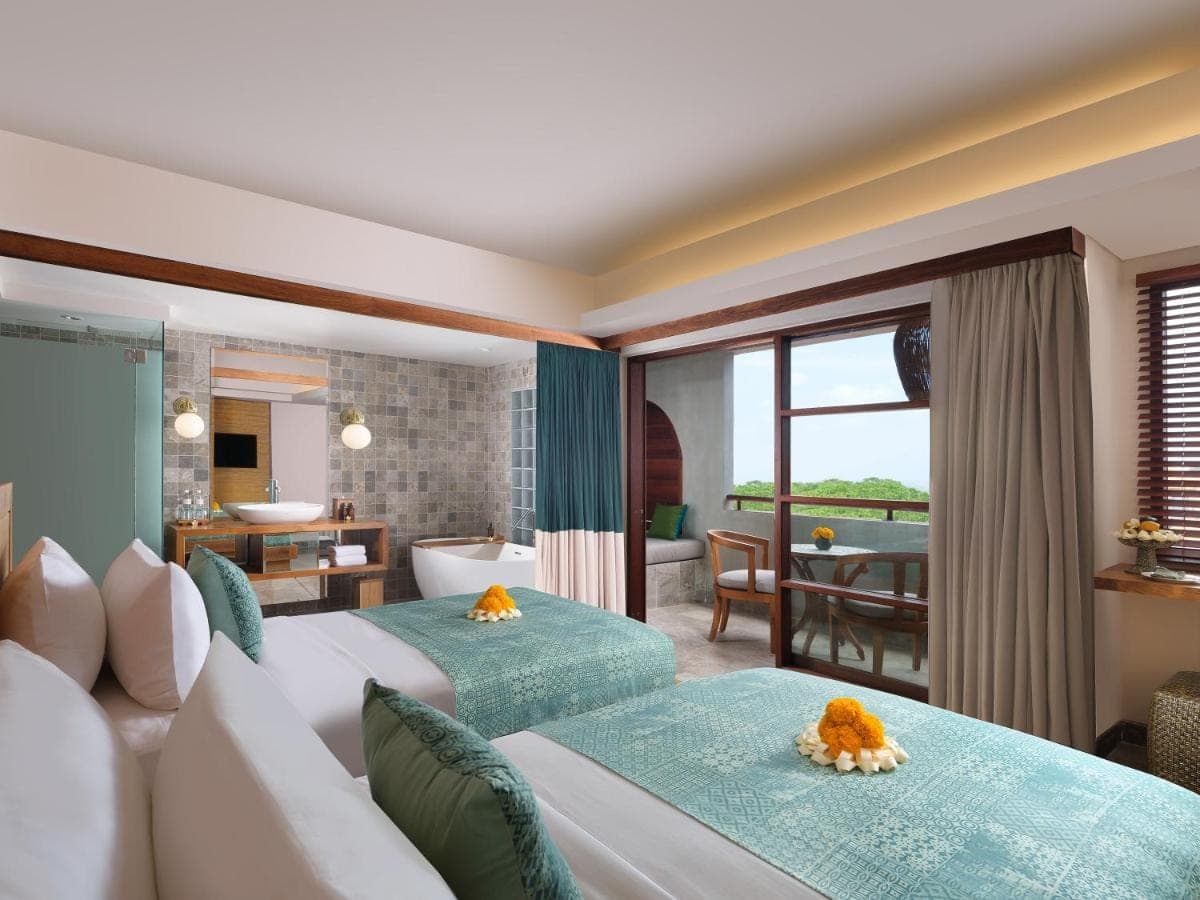 a bedroom with two beds and a living room at Amnaya Resort Nusa Dua in Nusa Dua