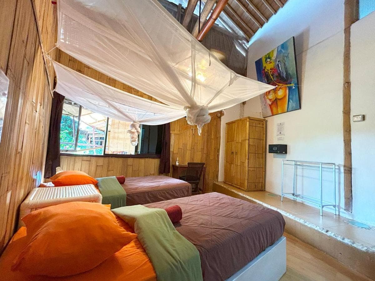 two beds in a room with a canopy over them at Serenity Eco Guesthouse and Yoga- CHSE certified in Canggu