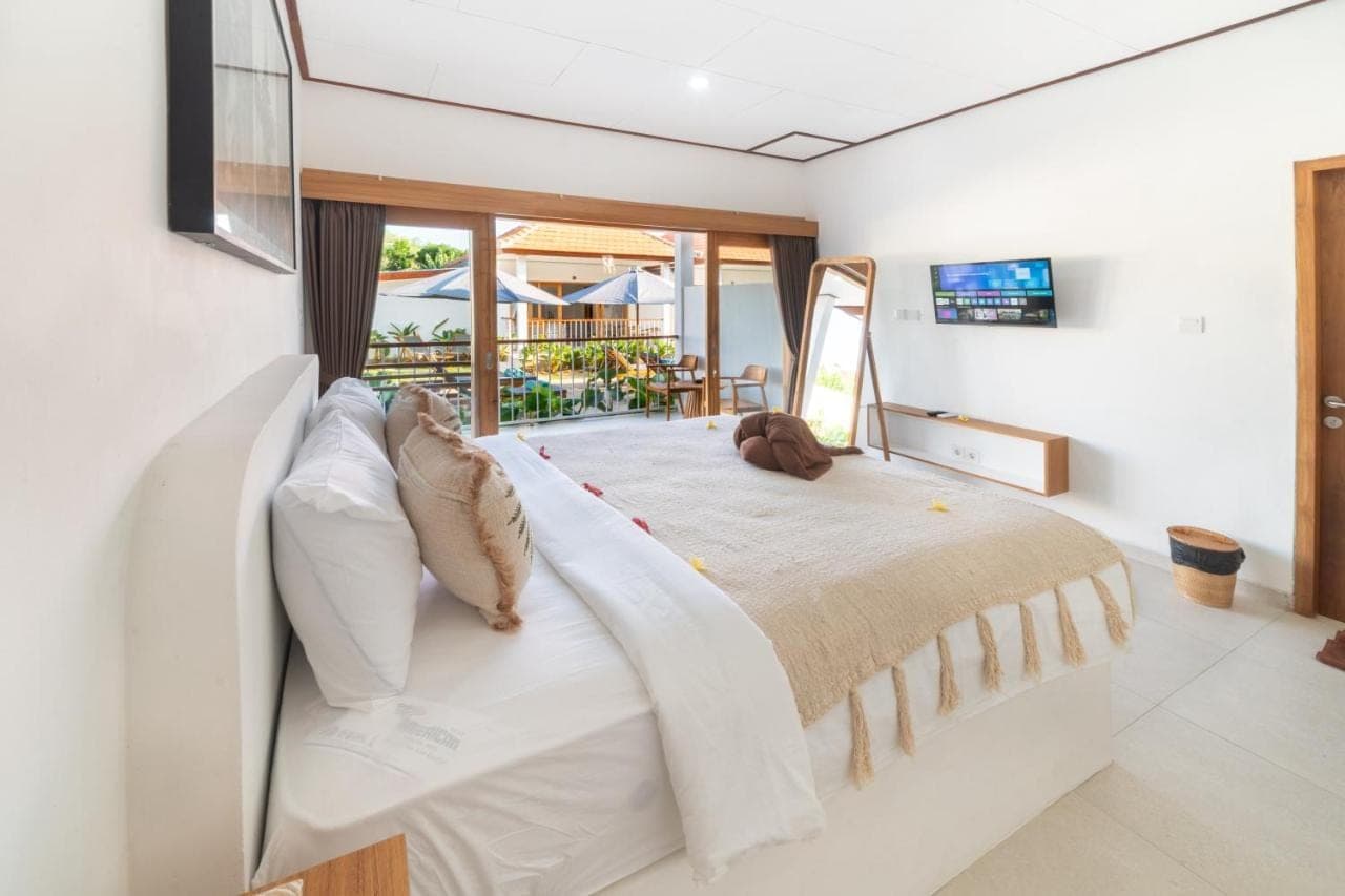 a bedroom with a large bed with a large window at Wodis Uluwatu in Uluwatu