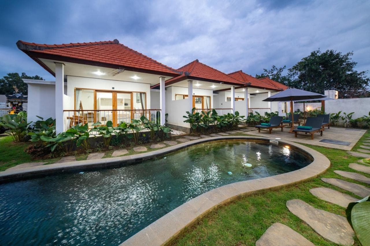 a villa with a swimming pool in front of a house at Wodis Uluwatu in Uluwatu