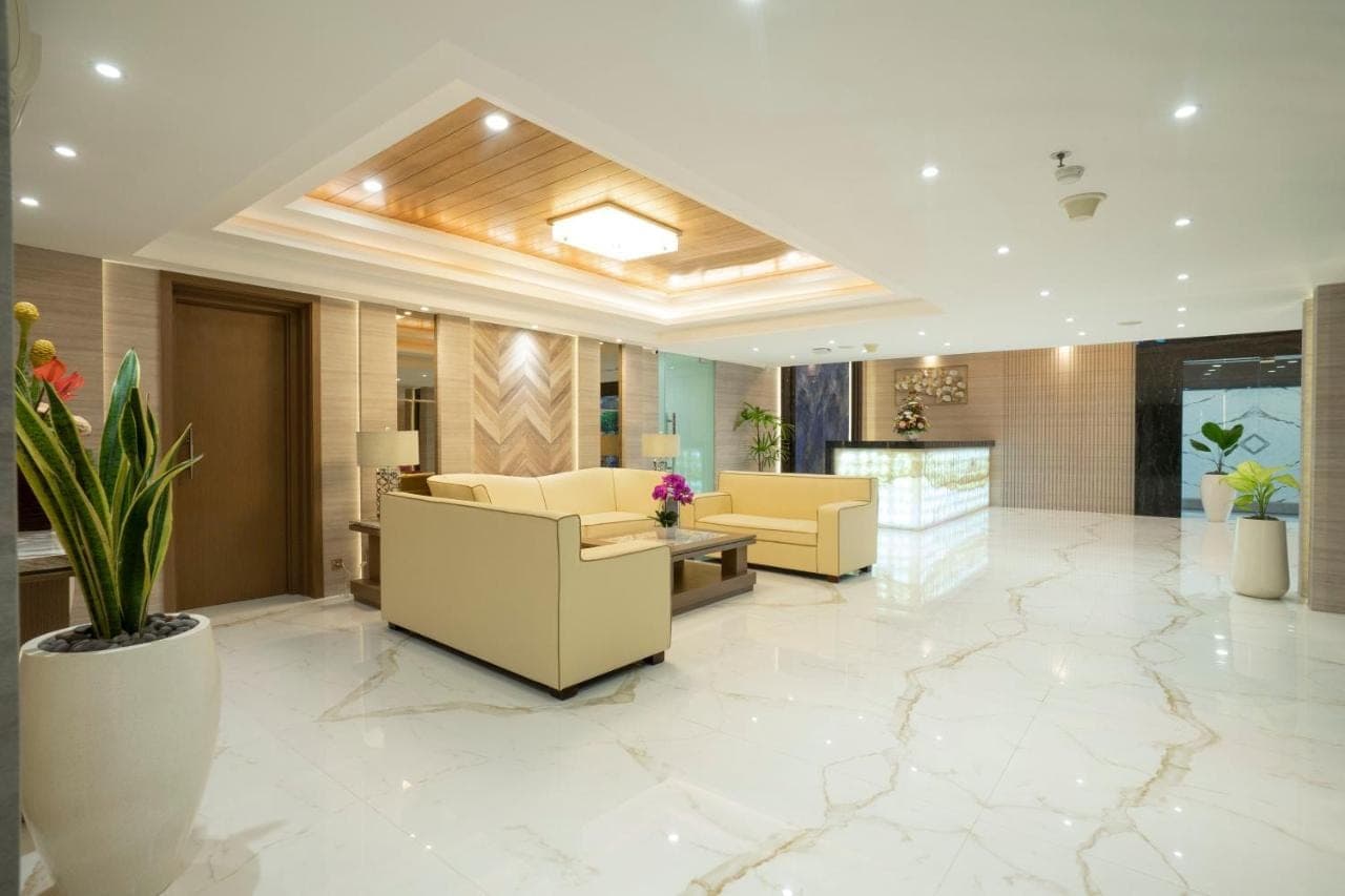 a lobby with couches and plants in a building at Sunrise Aventus Hotel Nusa Dua in Nusa Dua
