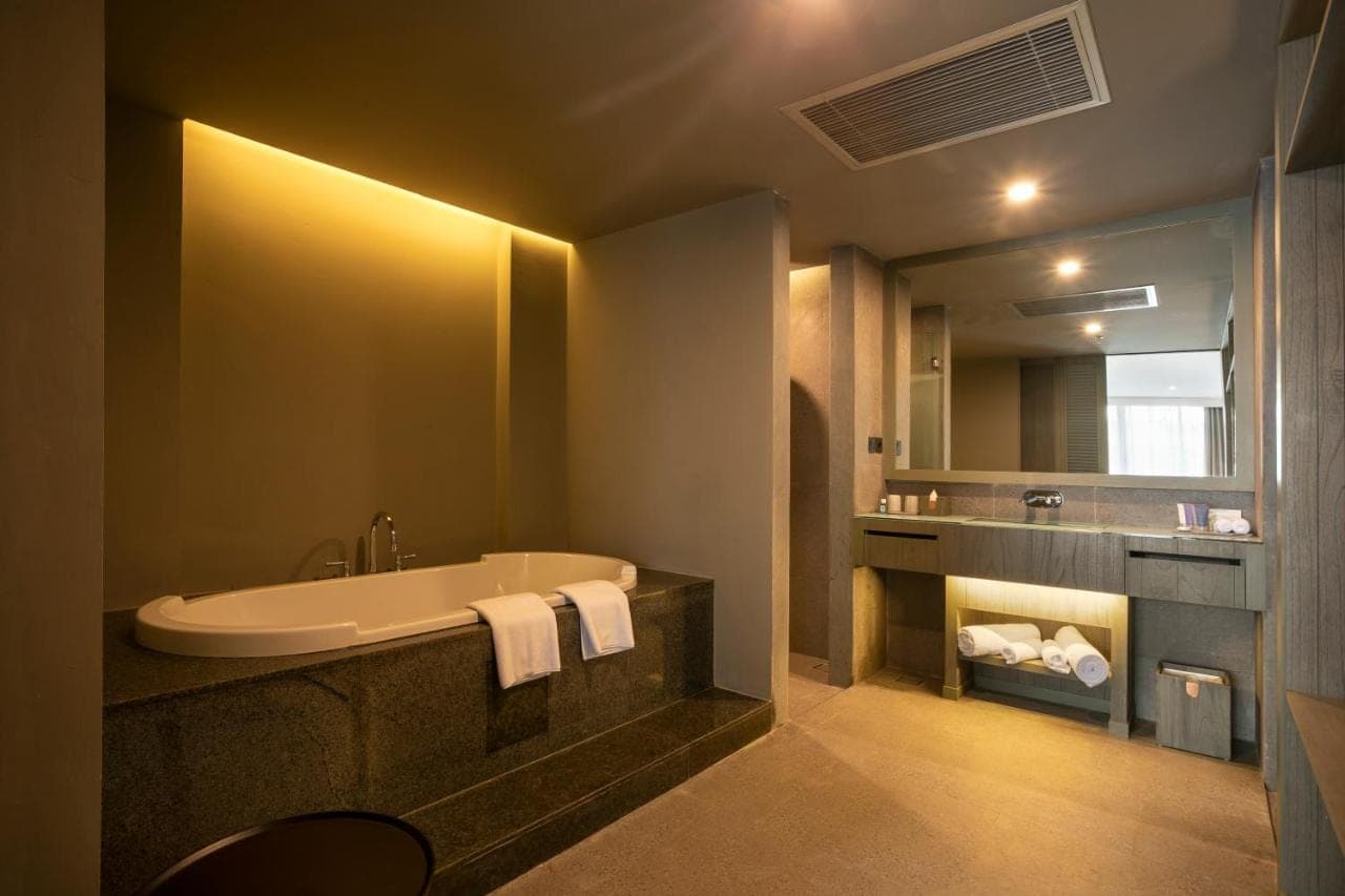 a bathroom with a tub and a sink and a mirror at Kanvaz Village Resort Seminyak in Seminyak