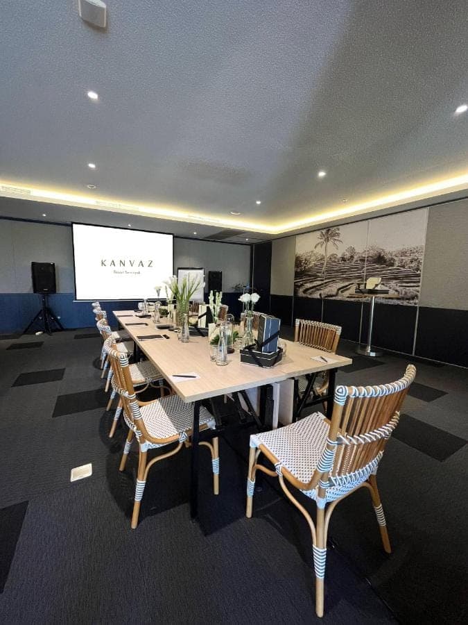a conference room with a table and chairs and a screen at Kanvaz Village Resort Seminyak in Seminyak