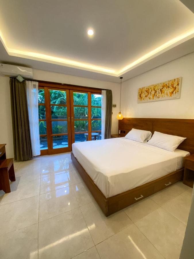 a bedroom with a large bed and a large window at Malaka pedati homestay in Uluwatu