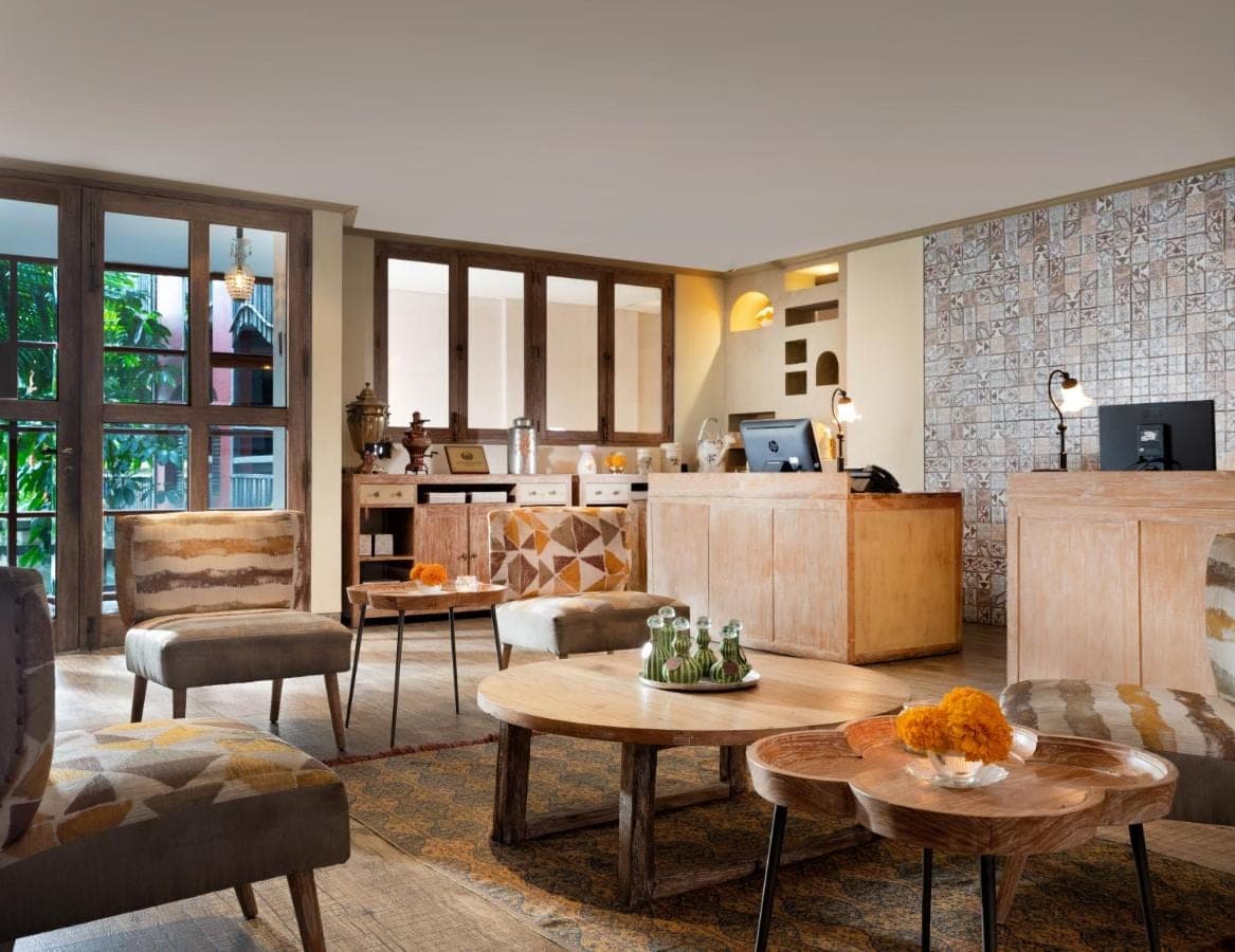 a living room with tables and chairs and a kitchen at Amnaya Resort Kuta in Kuta