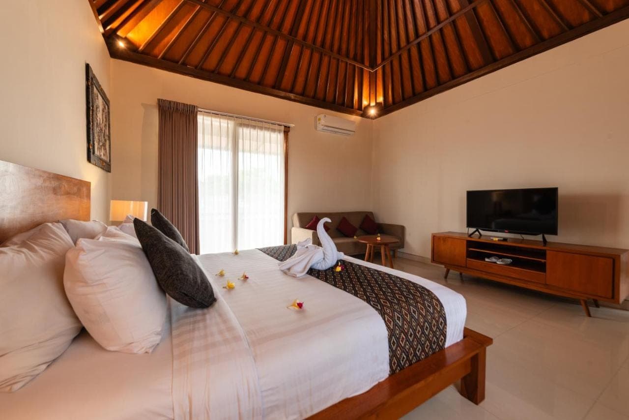 a bedroom with a large white bed with a television at Bali Ayu Hotel & Villas 10 Minutes Walking Distance to the Beach in Seminyak