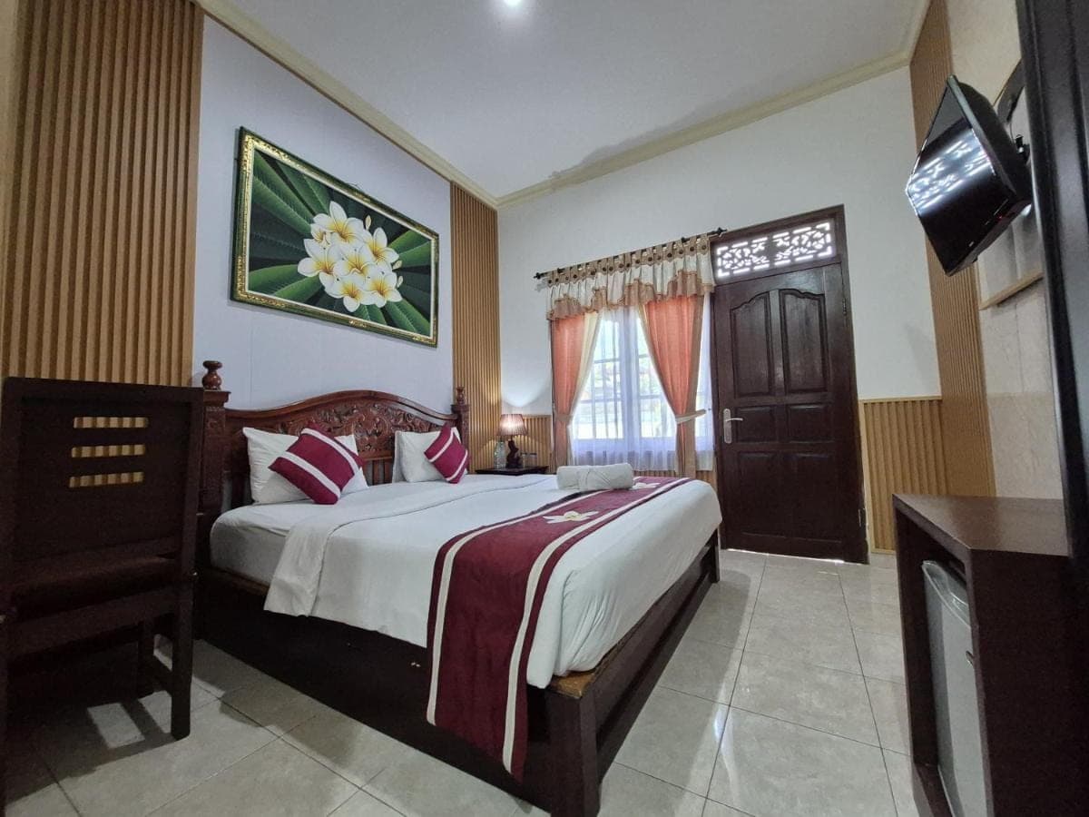 a bedroom with a large bed and a window at Frangipani Homestay in Nusa Dua