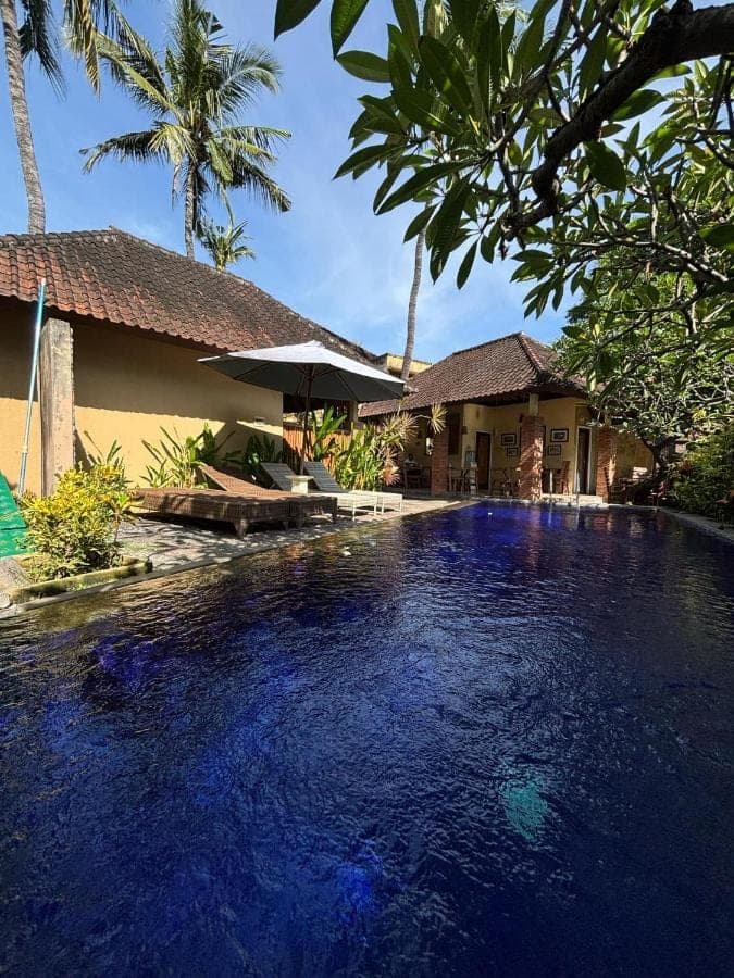 a swimming pool in front of a house at Petit Boo Amed in Amed