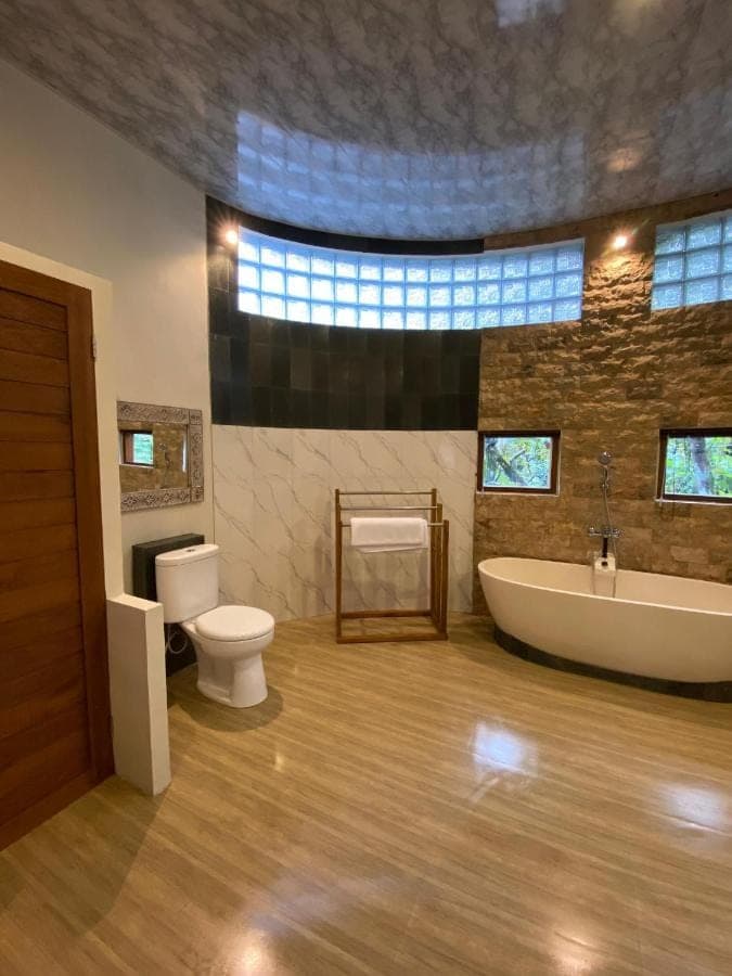 a bathroom with a tub and a toilet and a sink at Sunya Giri Lodge & Retreat in Sidemen
