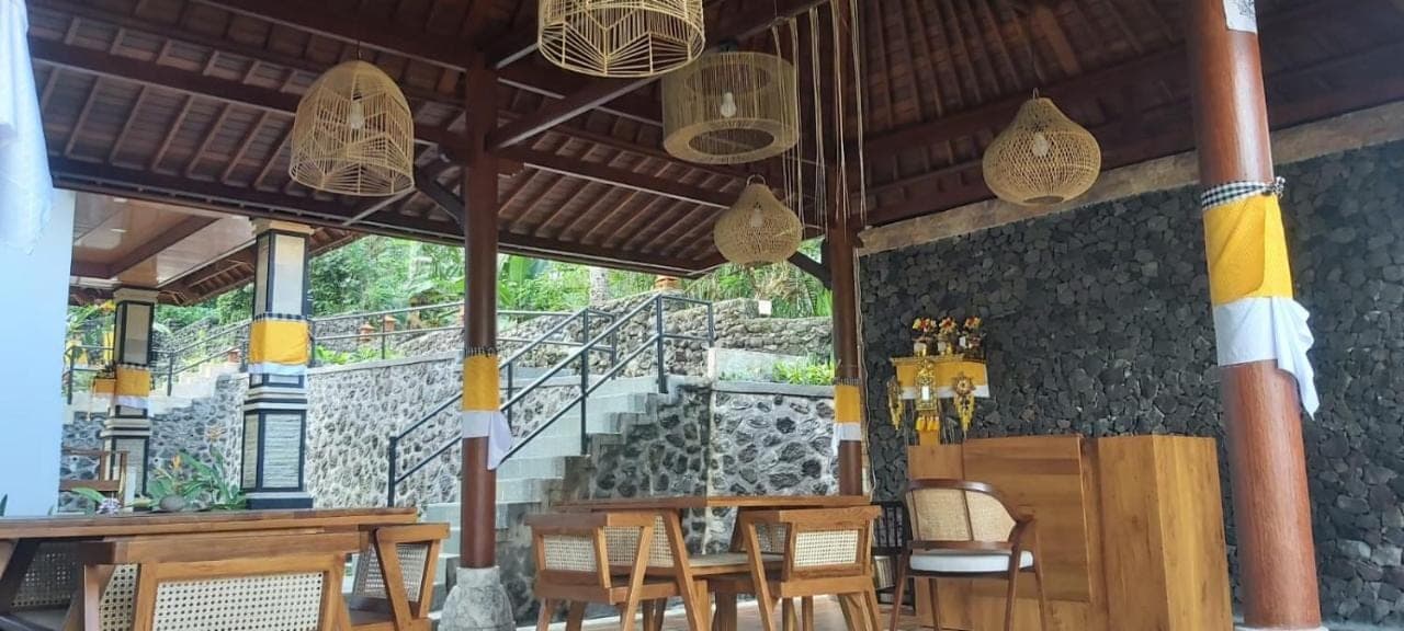 a restaurant with wooden tables and chairs and a staircase at Sunya Giri Lodge & Retreat in Sidemen