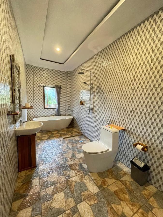 a bathroom with a tub and a toilet and a sink at Tirta Unda Sidemen in Sidemen