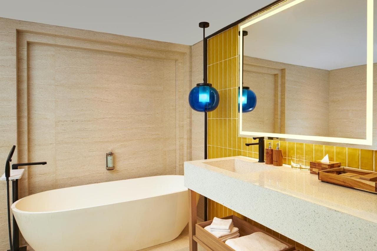a bathroom with a tub and a sink and a mirror at voco Bali Seminyak by IHG in Seminyak