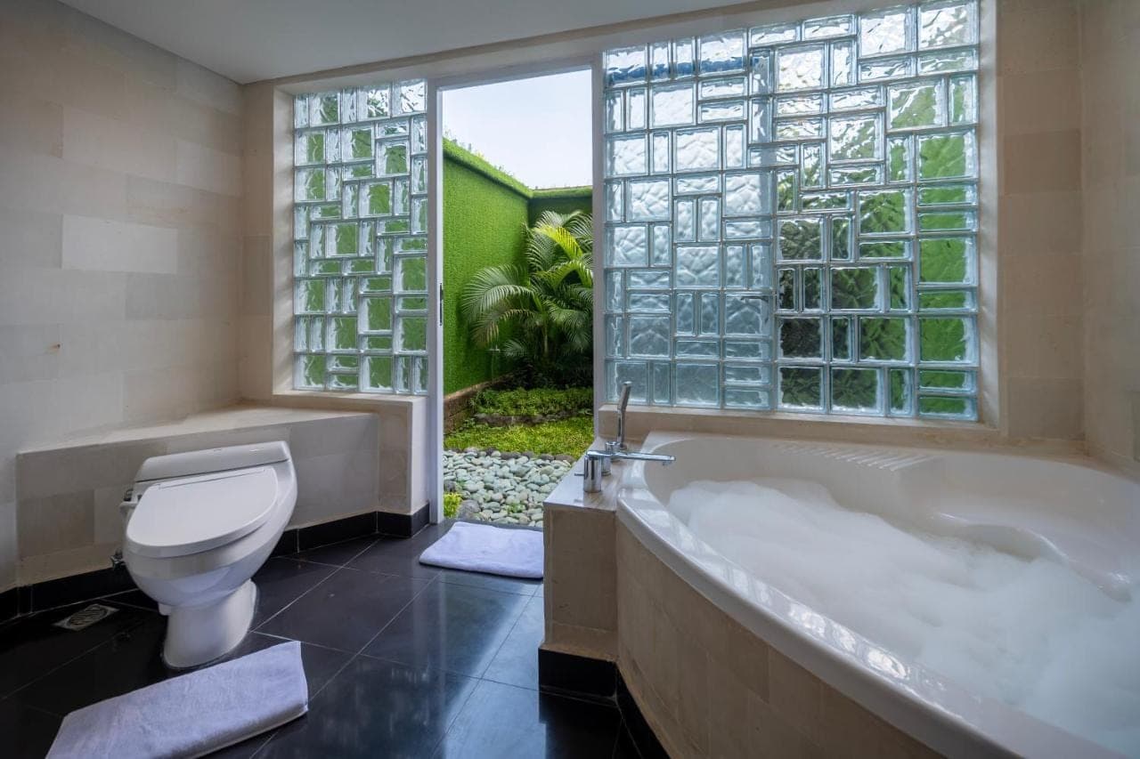 a bathroom with a tub and a toilet and a window at Prime Plaza Hotel Sanur \u2013 Bali in Sanur