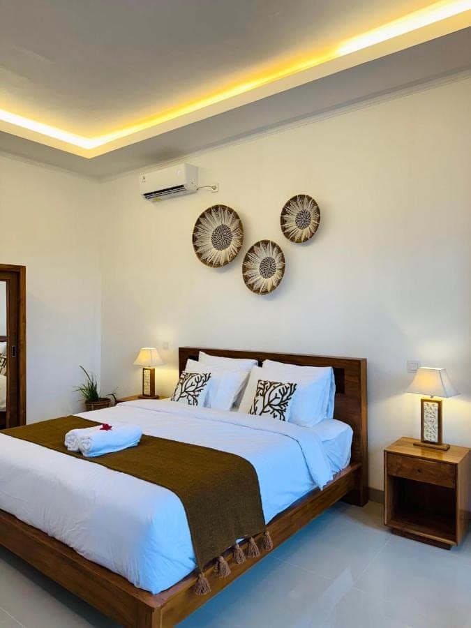 a bedroom with a large bed and two mirrors on the wall at South Hill Pandawa in Nusa Dua