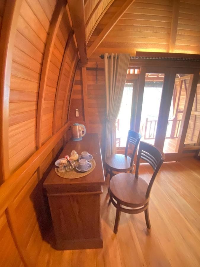 a room with a table and chairs in a cabin at Sri Sedana Homestay in Sidemen