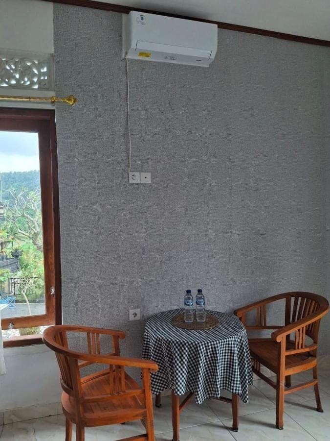 a table with two chairs and a table with two bottles on it at Sri Sedana Homestay in Sidemen