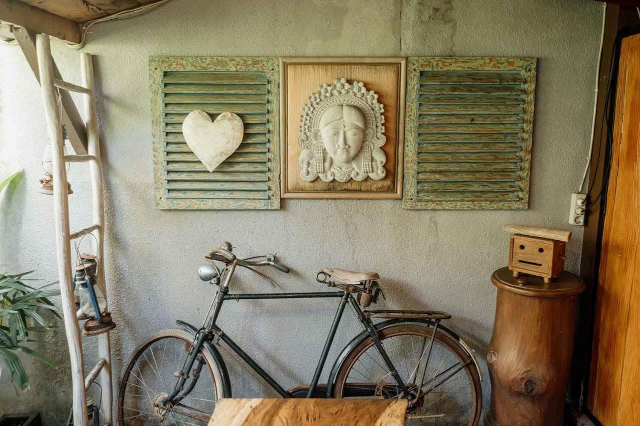 a bike parked next to a wall with a statue at Kemala Living Sanur in Sanur