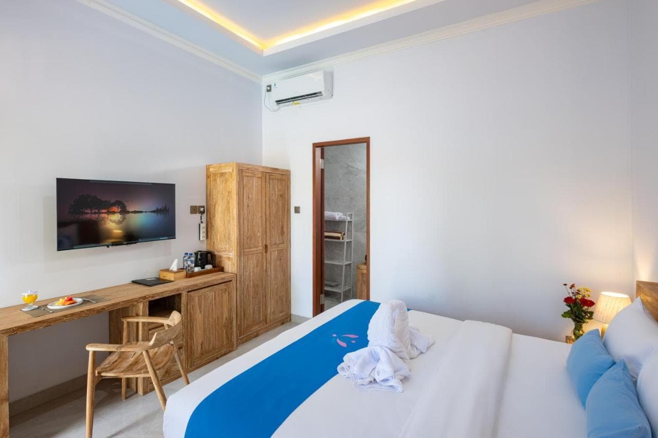 a bedroom with a bed and a desk and a tv at Kemala Living Sanur in Sanur