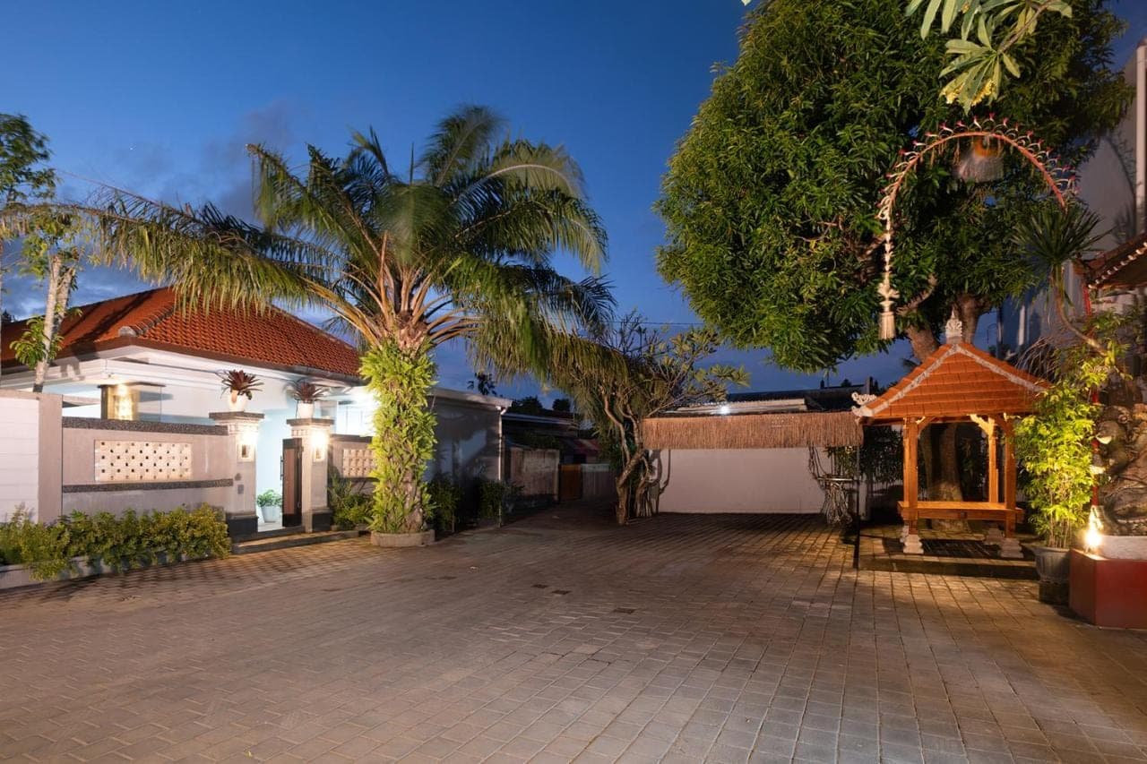 a courtyard of a house with palm trees and a building at Kemala Living Sanur in Sanur