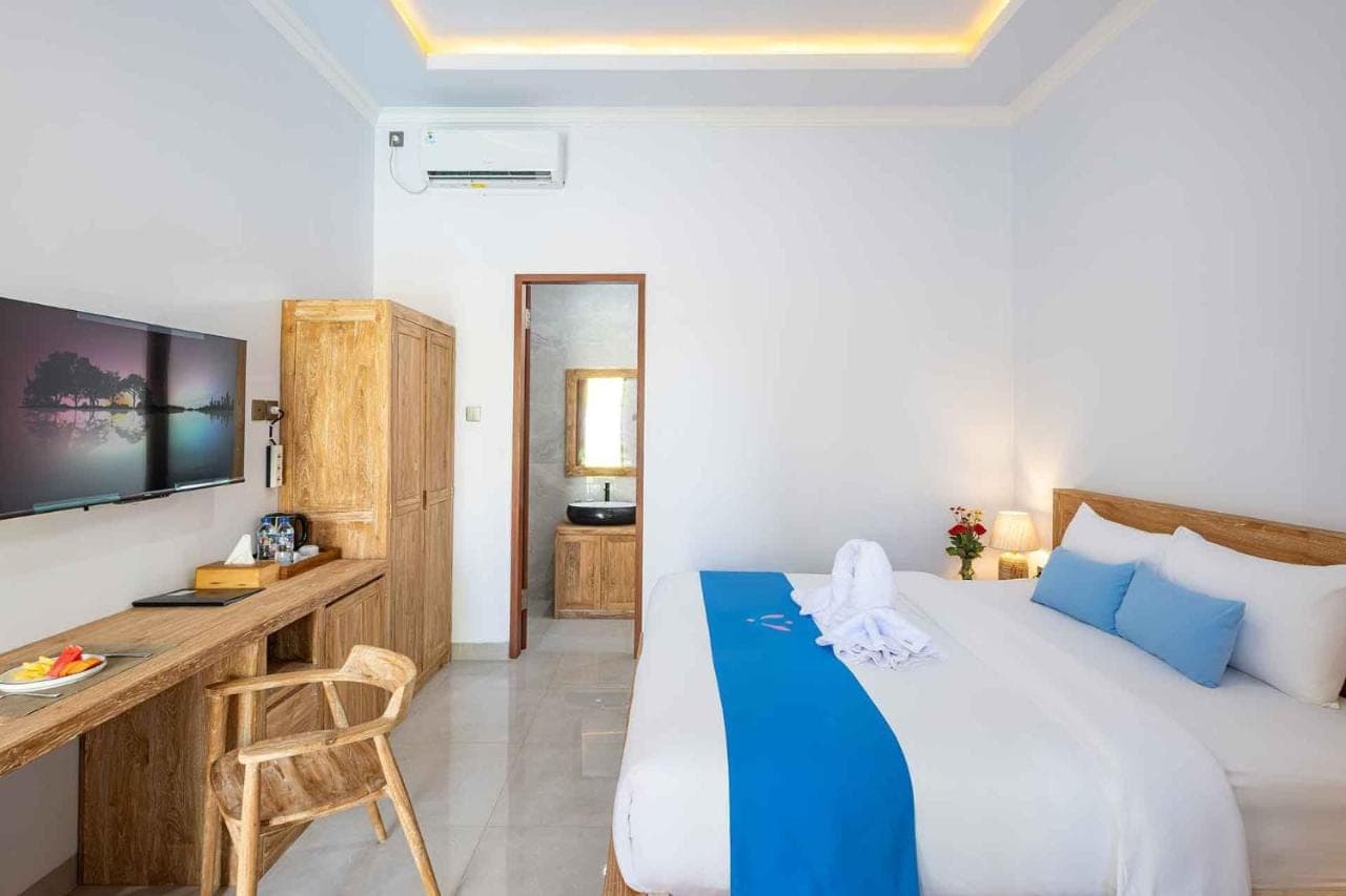 a bedroom with a bed and a desk and a television at Kemala Living Sanur in Sanur