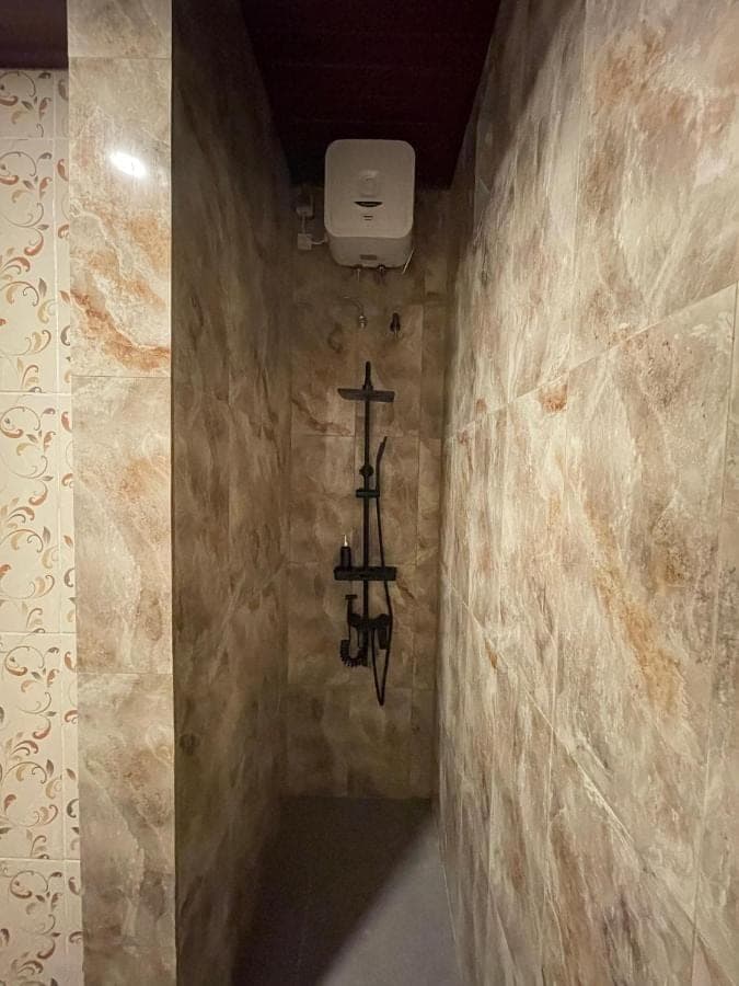 a bathroom with a cross hanging on the wall at Pradnya Homestay Ungasan - Room near Uluwatu in Uluwatu