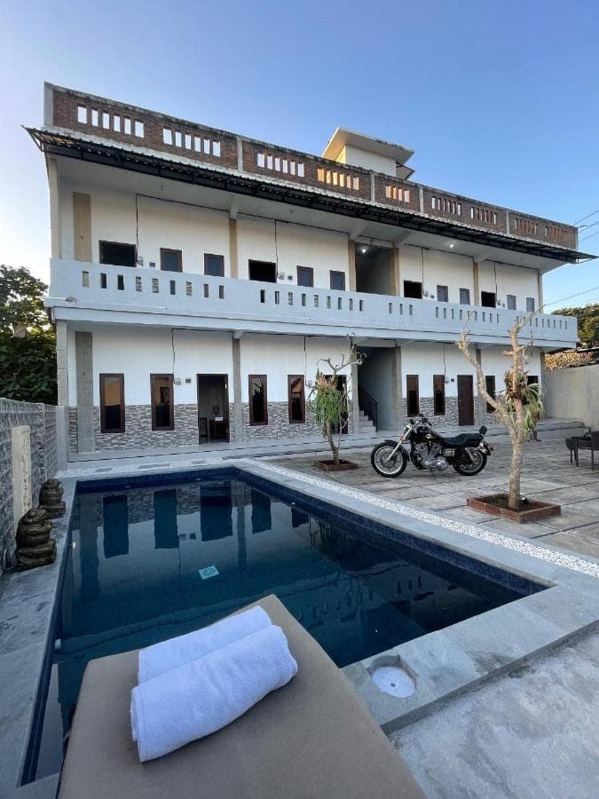 a hotel with a swimming pool in front of a building at Pradnya Homestay Ungasan - Room near Uluwatu in Uluwatu