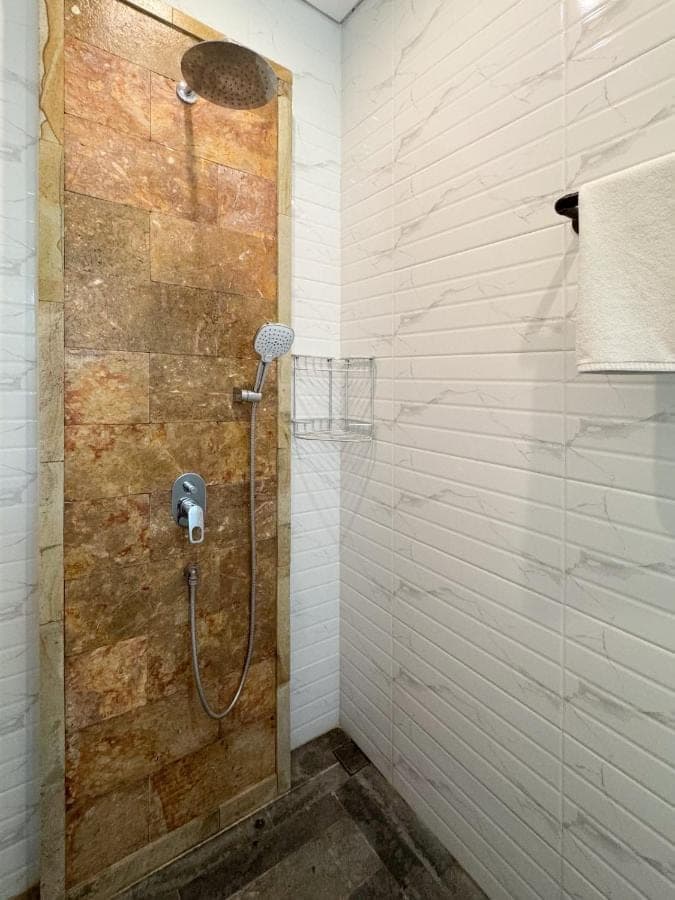 a shower with a shower head in a bathroom at Indara private pool villa in Nusa Dua