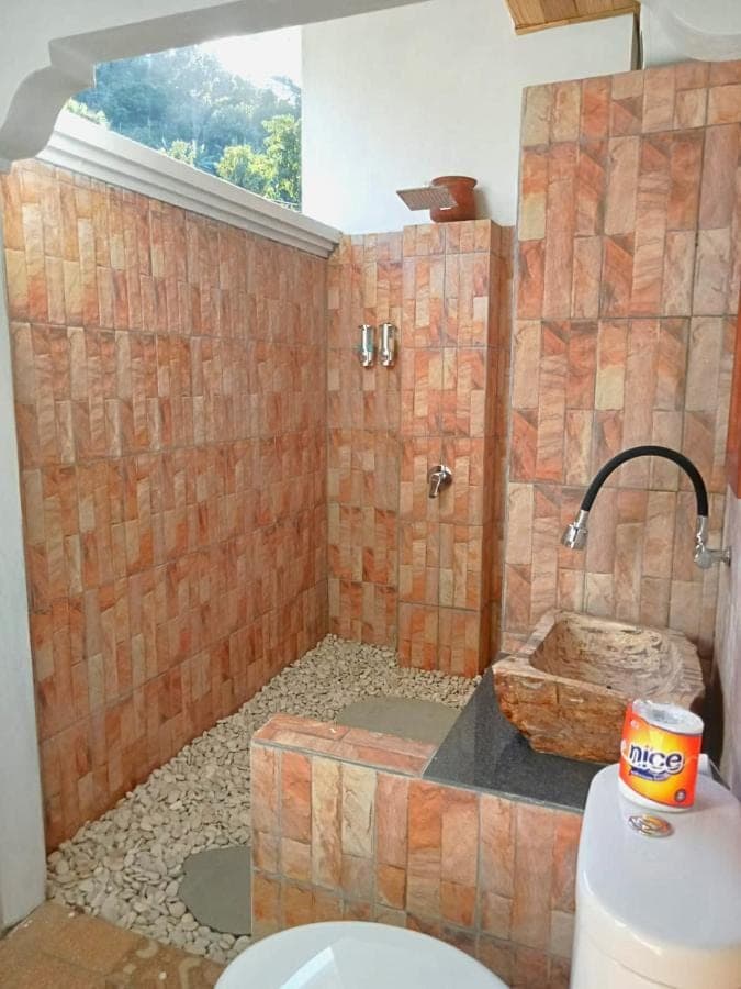 a bathroom with a toilet and a stone shower at Raweg Studio in Amed