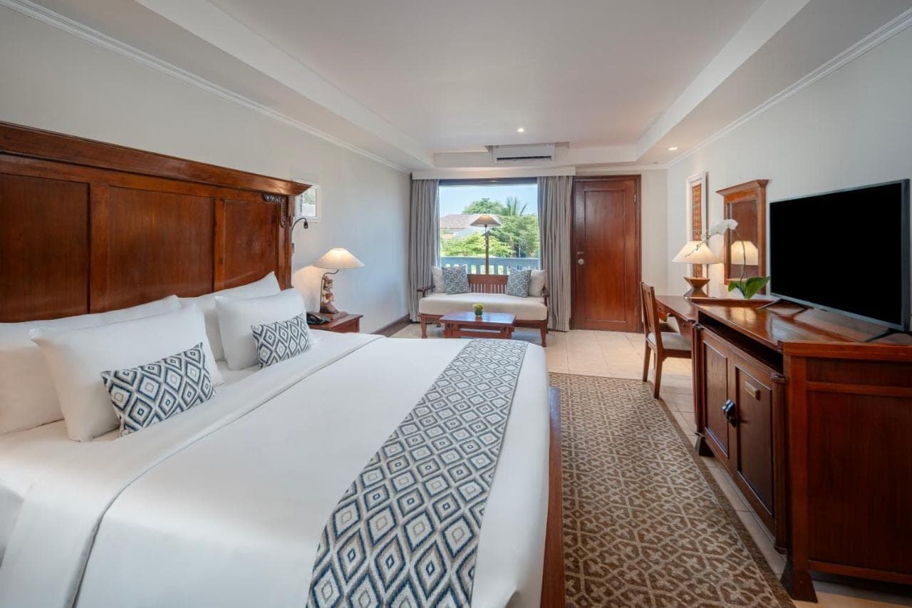a bedroom with a large bed and a flat screen tv at Ramayana Suites and Resort in Kuta