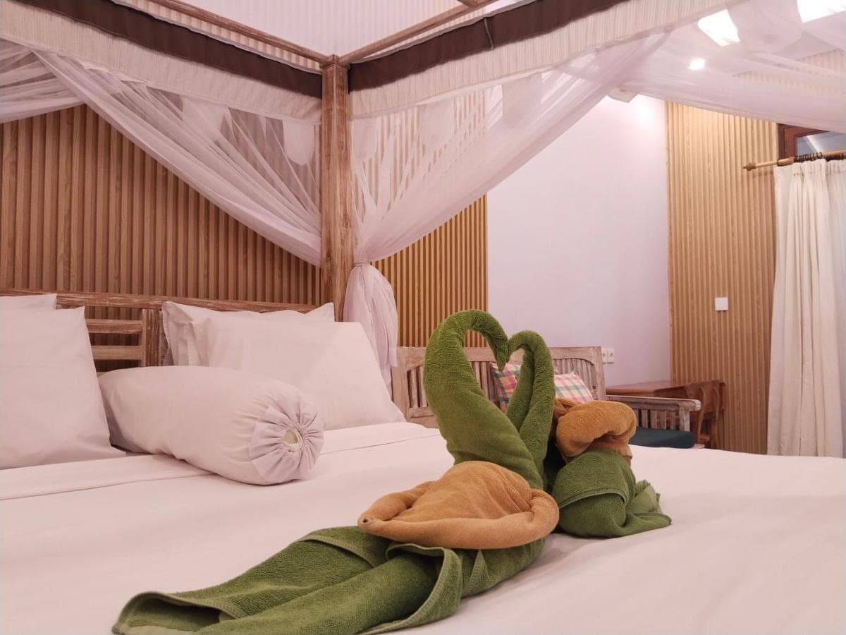two stuffed animals are laying on a bed at Sama Sama Amed in Amed