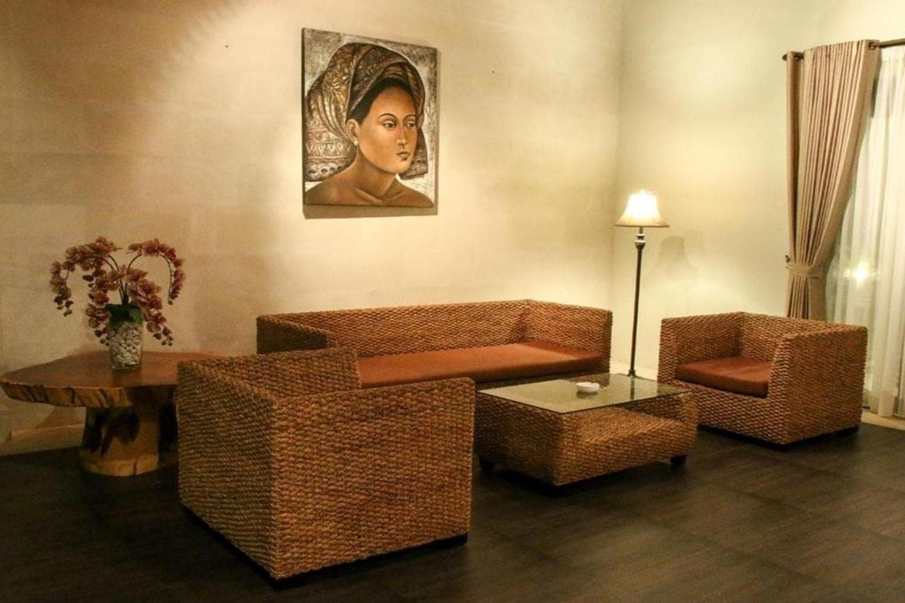 a living room with wicker furniture and a painting on the wall at Linda Villa Sanur by Linda in Sanur