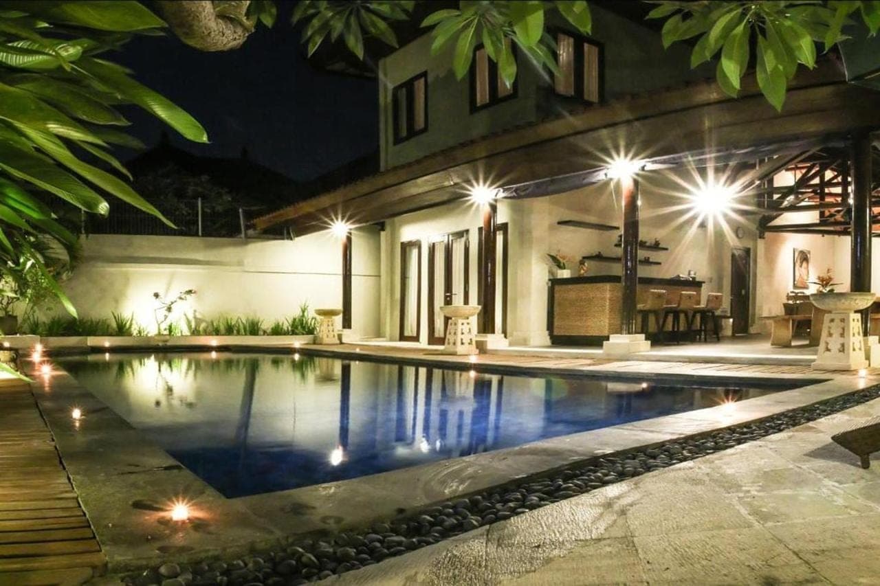 a swimming pool in front of a house at night at Linda Villa Sanur by Linda in Sanur