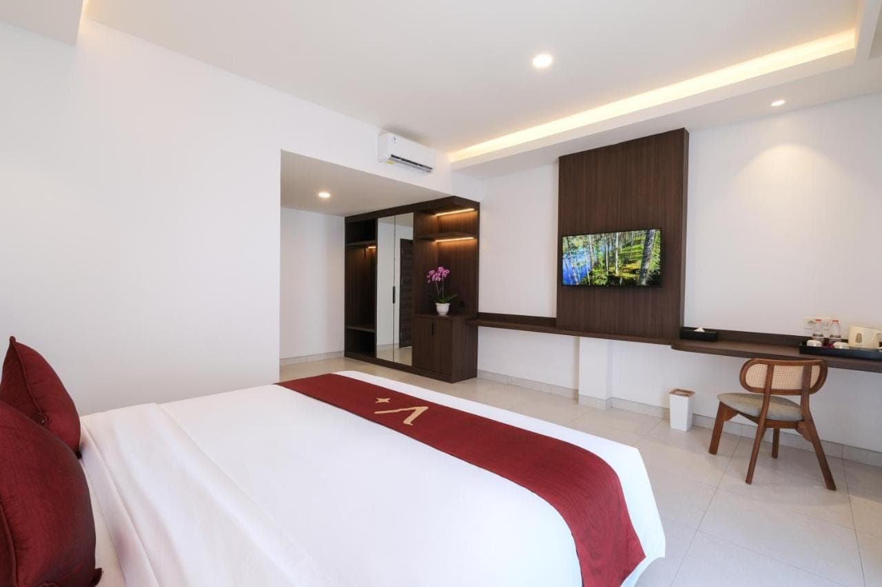 a bedroom with a large bed and a desk at ValStar Hotel Canggu in Canggu