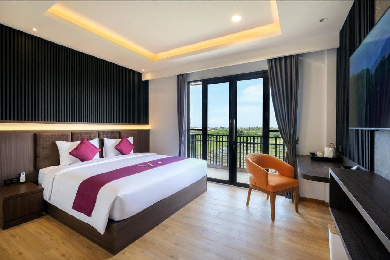 a bedroom with a large bed and a balcony at ValStar Hotel Canggu in Canggu