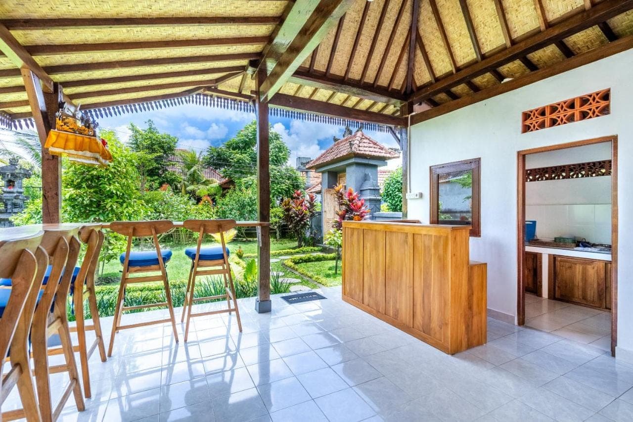 a kitchen with a bar with stools and a view at Lumbung Sari villa ubud by Dewanta Property in Ubud