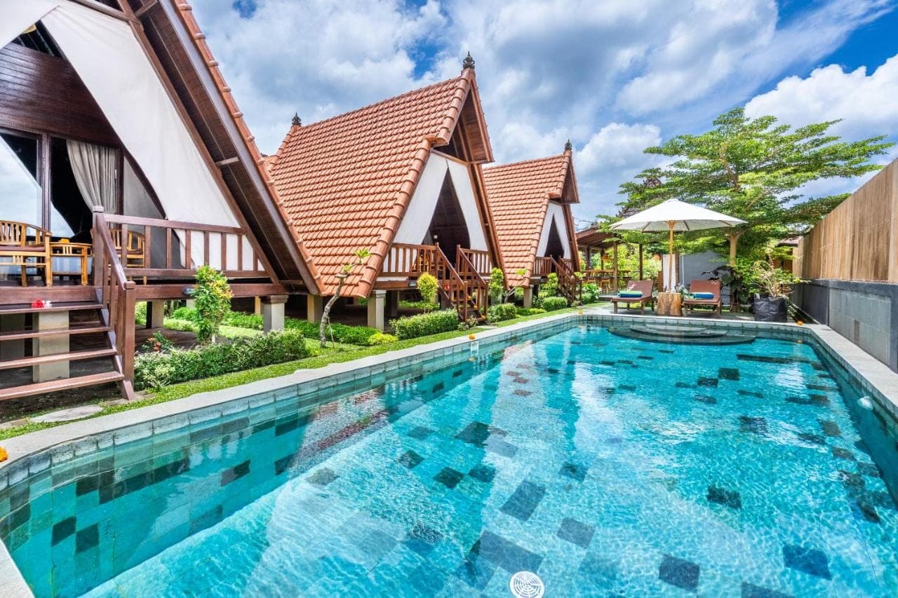 a large swimming pool in front of a house at Lumbung Sari villa ubud by Dewanta Property in Ubud