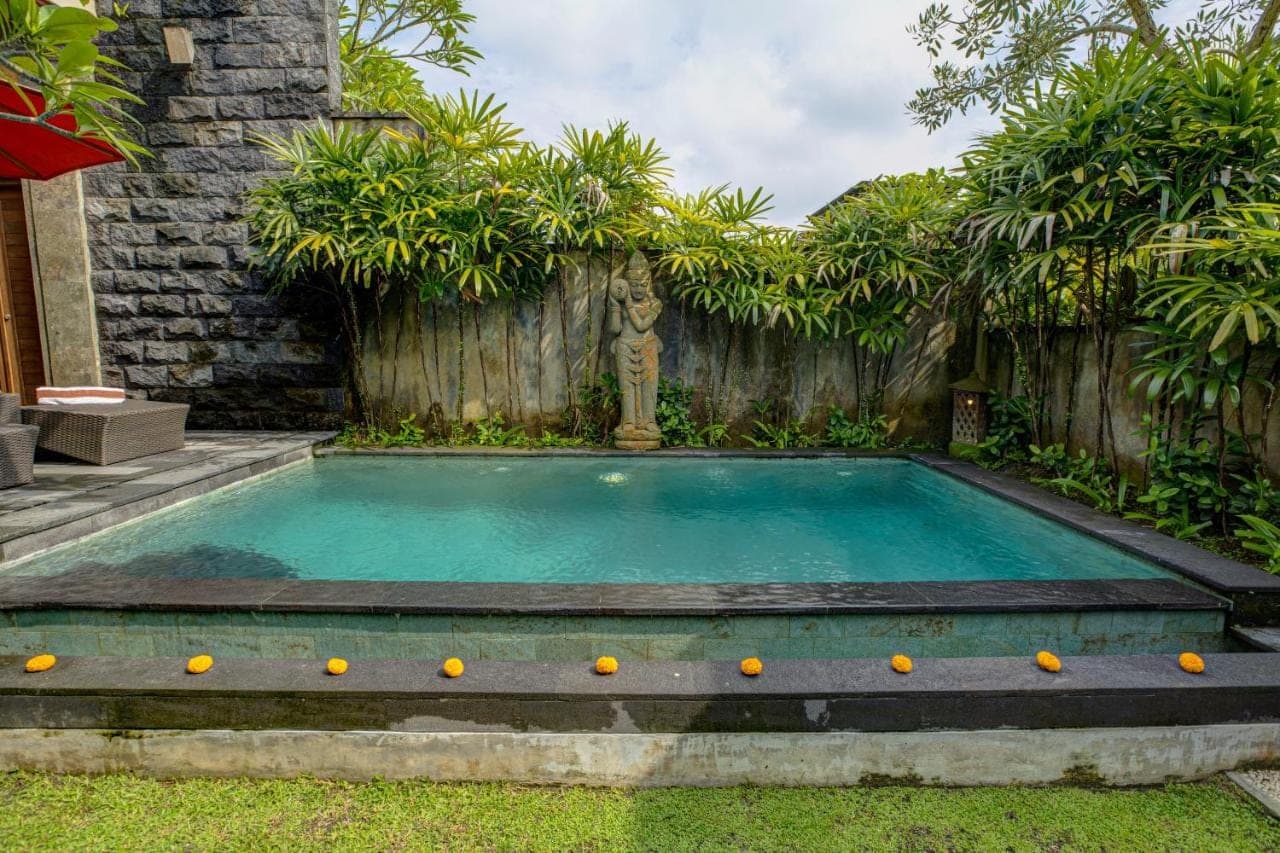 a swimming pool in a backyard with a wooden fence at Dupa Ubud in Ubud