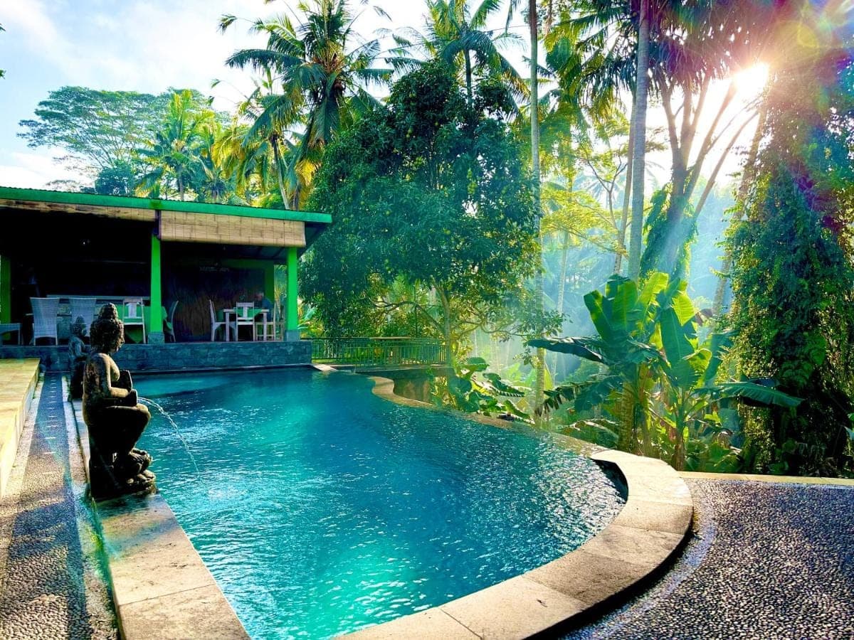 a woman sitting in front of a swimming pool at Dupa Ubud in Ubud