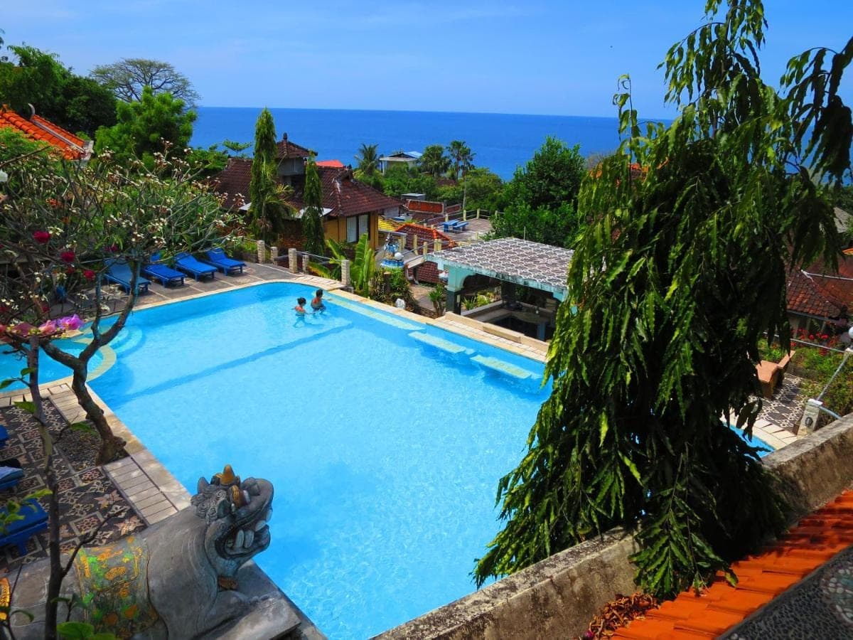 a large swimming pool with people swimming in it at Amed Cafe & Hotel Kebun Wayan in Amed