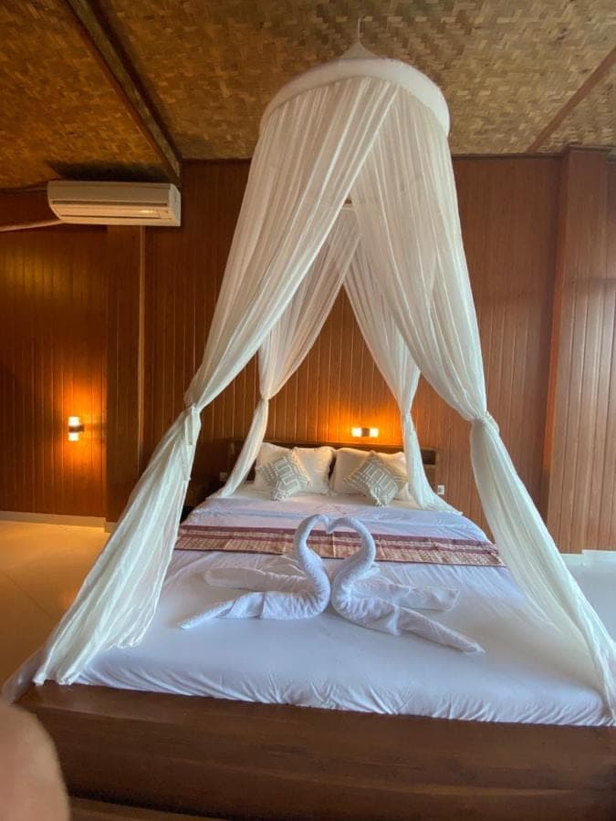 two swans laying on a bed with mosquito nets at Villa Lumbung Ayu Sari & Spa in Sidemen