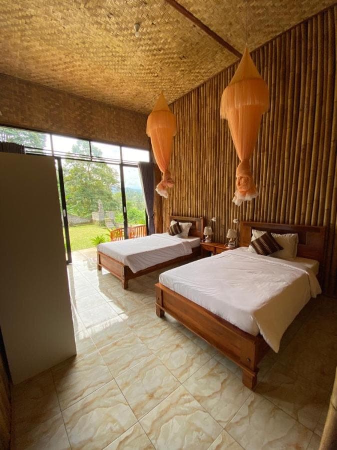 a bedroom with two beds and a large window at Villa Lumbung Ayu Sari & Spa in Sidemen