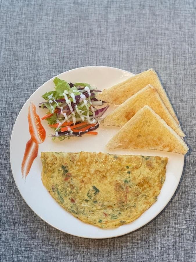 a white plate with an omelet and chips and a salad at Pondok Wana Ubud in Ubud