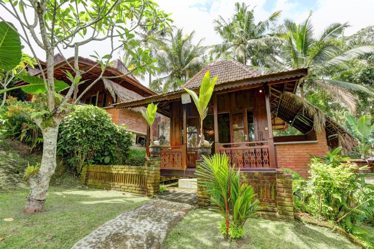 a house in a garden with a tree at Junjungan Suite in Ubud