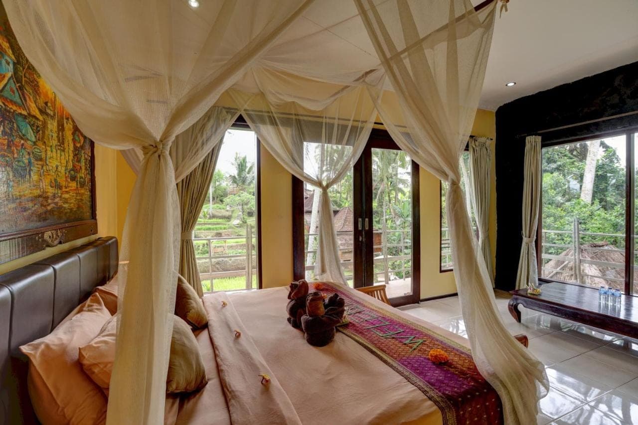a bedroom with a canopy bed with curtains and windows at Junjungan Suite in Ubud