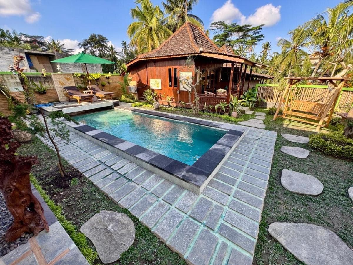 a swimming pool in front of a house at Junjungan Suite in Ubud