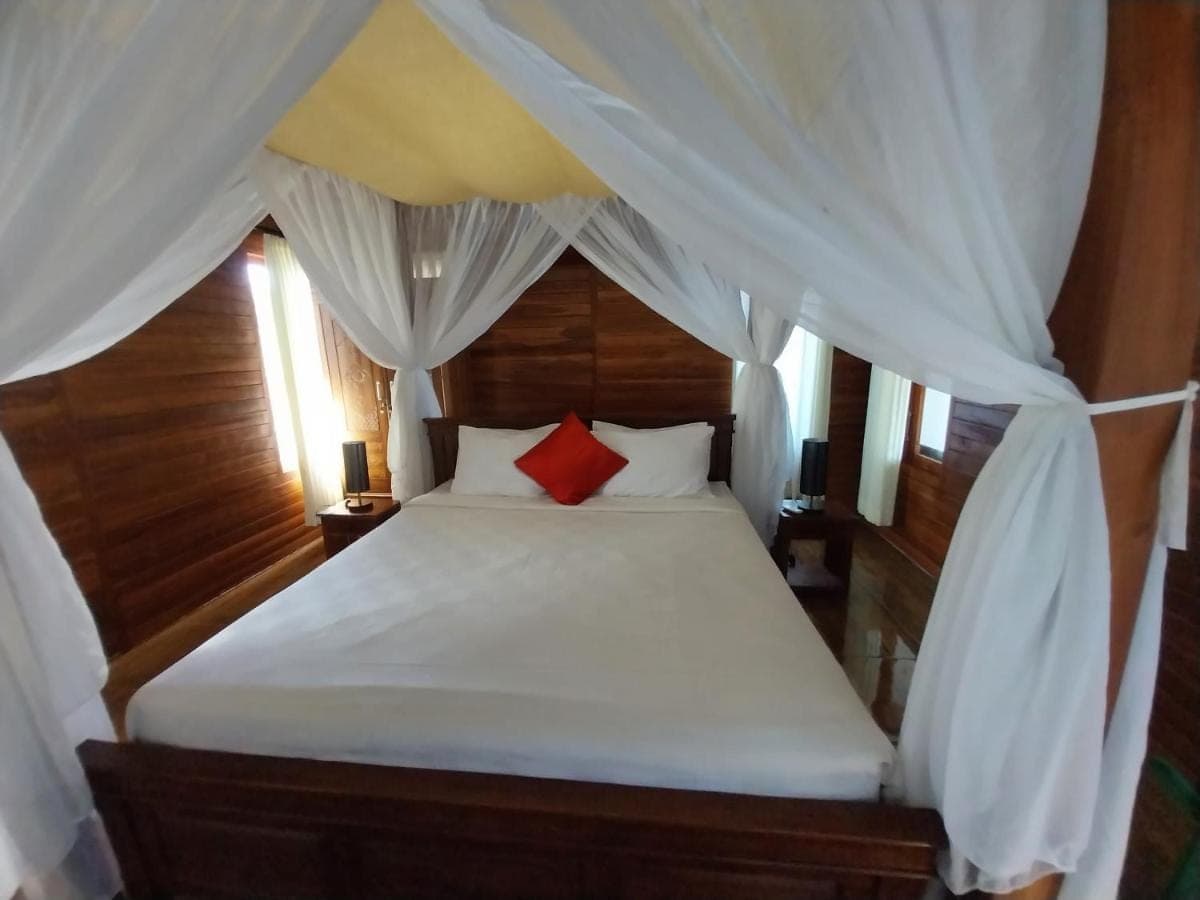 a bedroom with a white bed with red pillows at D,Jajang Guest House in Nusa Dua