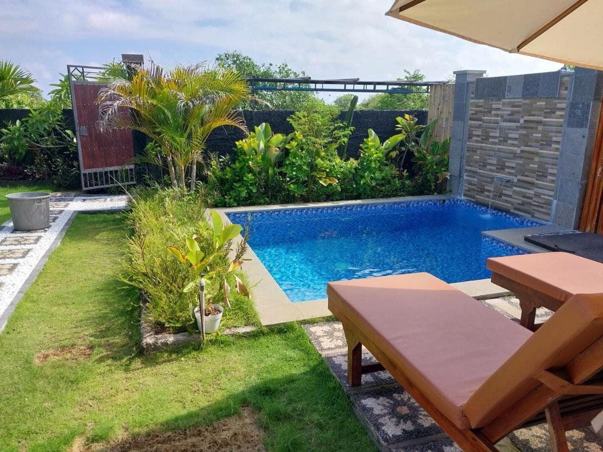 a swimming pool in a backyard with a table and a table sidx sidx at D,Jajang Guest House in Nusa Dua