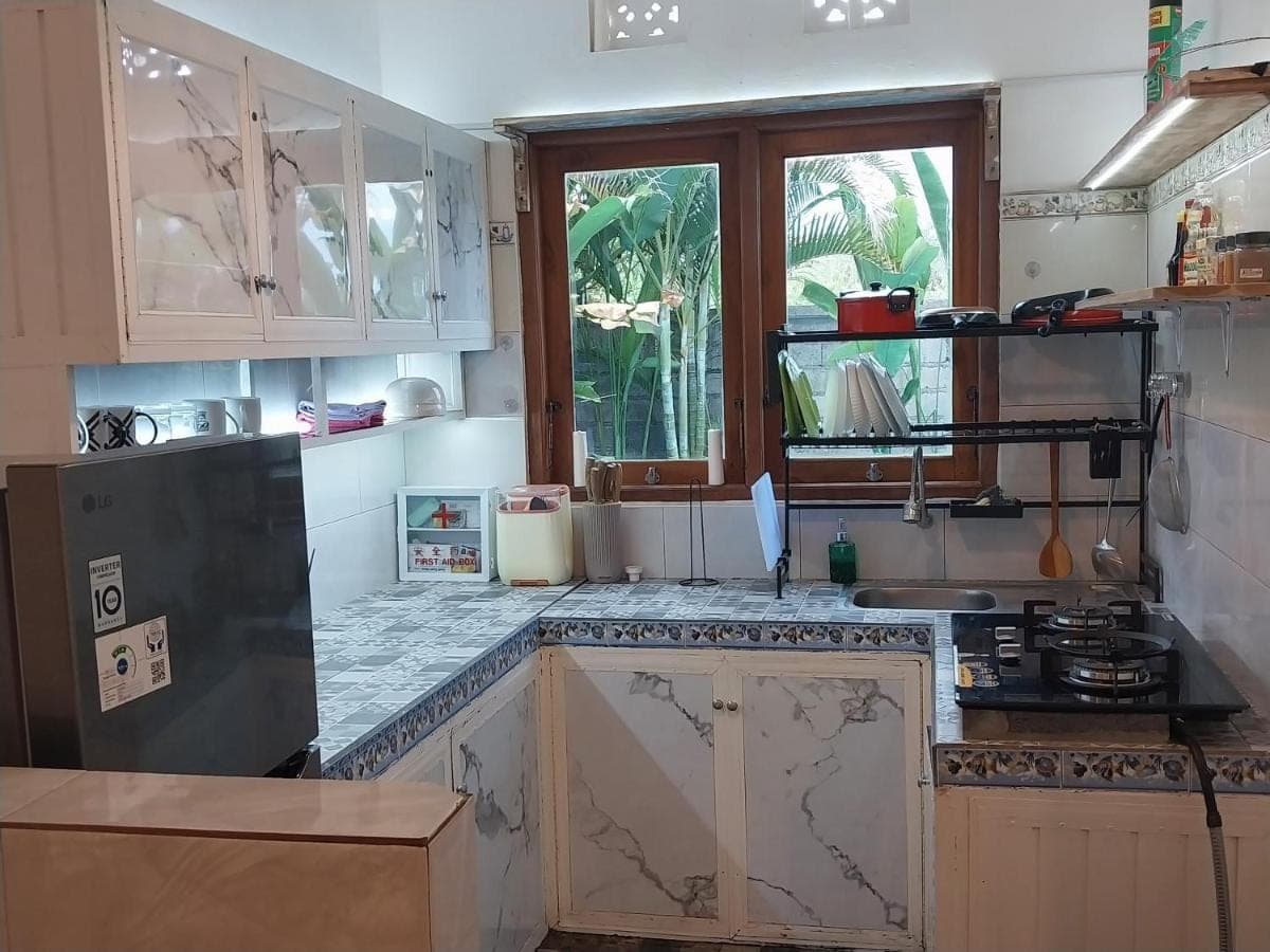 a kitchen with white cabinets and a black refrigerator at D,Jajang Guest House in Nusa Dua