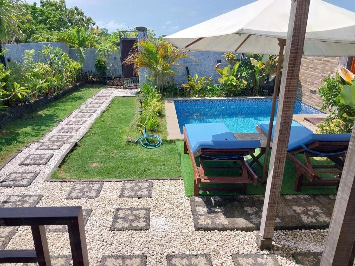 a patio with a table and chairs and an umbrella at D,Jajang Guest House in Nusa Dua